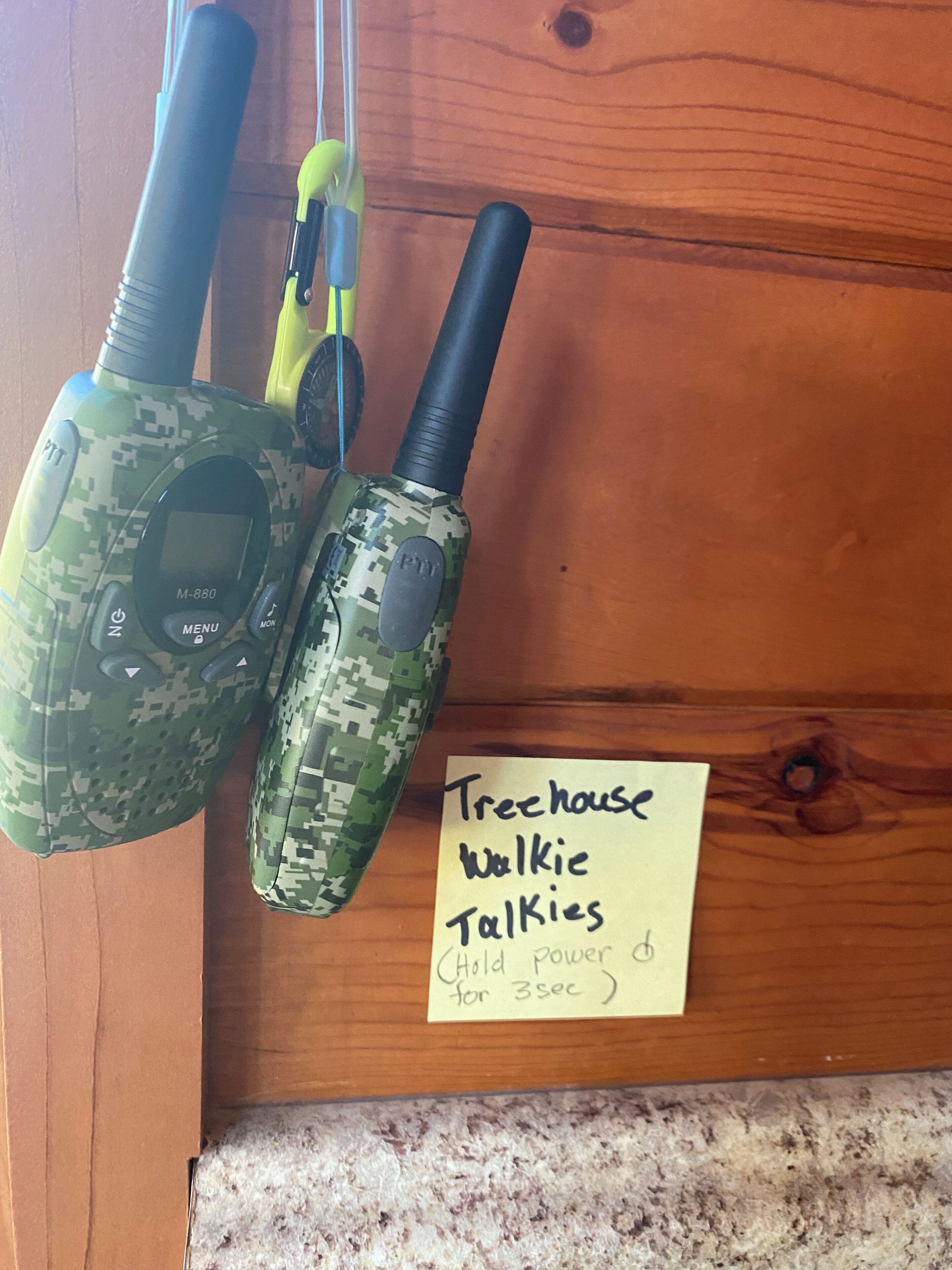 Two walkie-talkies on a wooden surface with a note that says "Treehouse Walkie Talkies".