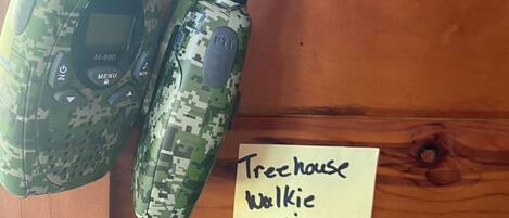 Two walkie-talkies on a wooden surface with a note that says "Treehouse Walkie Talkies".