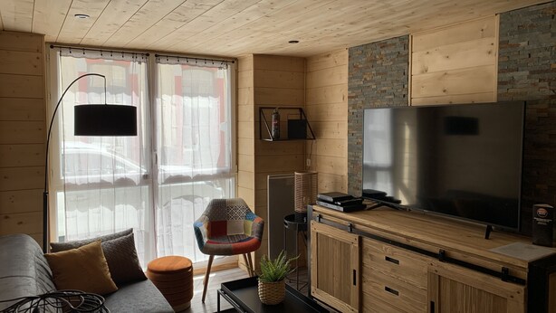 A compact living space with a sofa, a coffee table, a TV, and wooden cabinets.