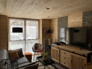 A compact living space with a sofa, a coffee table, a TV, and wooden cabinets. - COZY APARTMENT IN THE CITY CENTER, SLEEPS 8, Wi-Fi, 2 Private Parking Spaces (Cauterets)