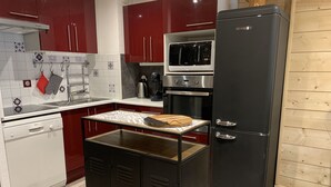 A kitchen with red cabinets, a black refrigerator, a microwave, and a Bosch dishwasher.