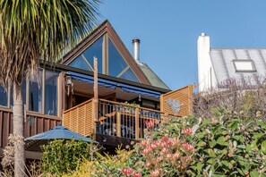A modern house with a balcony, large windows, and a chimney.