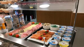 A buffet with various food items including meats, cheeses, and dairy products.