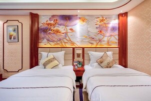 A hotel room with two beds, a large floral mural on the wall, and a small table between the beds.