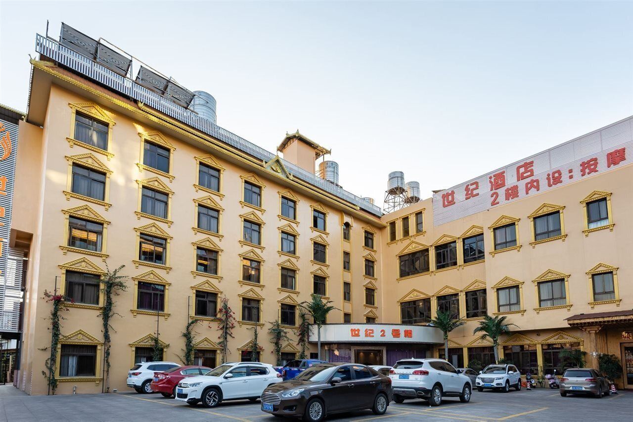 Un hotel de varios pisos, un estacionamiento con varios coches y un cartel que indica el nombre y los servicios del hotel.