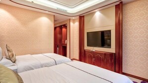 Una habitación de hotel con dos camas, un televisor montado en la pared y un armario de madera.