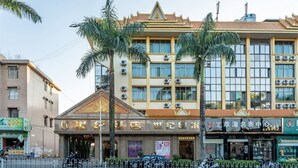 Un hotel de estilo arquitectónico tradicional, con una entrada destacada que incluye un techo decorativo y varios equipos de aire acondicionado.