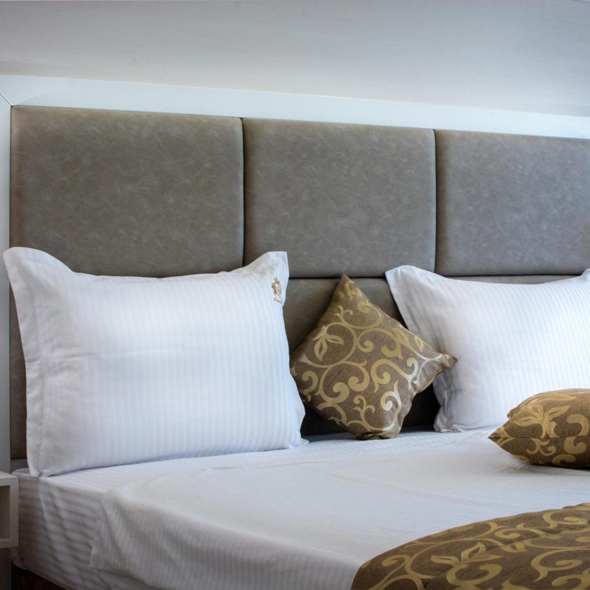 A bed with a headboard, white bedding, and decorative pillows.