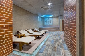 A spa area with sun loungers, a stone wall, and a logo on the wall. - Siena Palace (Primorsko)
