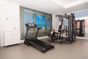 A home gym with a treadmill, weight machines, and a large mirror. - Siena Palace (Primorsko)