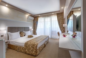 Una habitación de hotel moderna con una cama grande, un escritorio con espejo y un televisor.