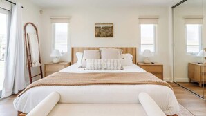 Un dormitorio con una cama grande, dos mesitas de noche, un cabecero de madera y un cuadro en la pared.