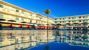 Ein Hotel mit Schwimmbad, mehreren Balkonen und Sonnenschirmen.