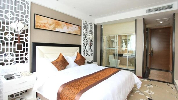 A modern hotel room with a large bed, a desk, and a bathroom visible through a glass door. - Gentleman Hotel (Shenzhen)