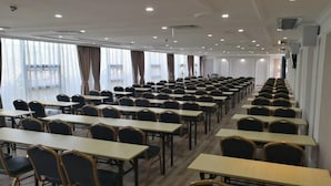 A conference room with rows of tables and chairs, large windows with curtains, and recessed ceiling lighting. - Gentleman Hotel (Shenzhen)