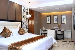 A hotel room with a large bed, a desk, and chairs. - Gentleman Hotel (Shenzhen)