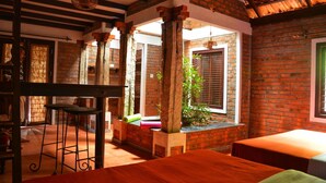 A room with a brick wall, wooden beams, and a window with blinds. - Annapara Home Stay (Vythiri)