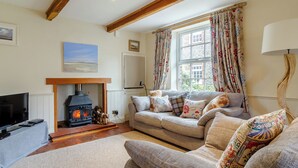 A cozy living room with a fireplace, a sofa, and a television. - 2 bedroom accommodation in Blakeney (Blakeney)