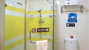 A bathroom with a glass door, a yellow and white tiled wall, a handrail, a towel rack, a toilet, and a shelf with towels. - 7 Days INN Xingguang Avenue (Nanning)