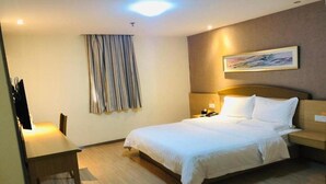 A hotel room with a bed, bedside table, lamp, and a painting on the wall. - 7 Days INN Xingguang Avenue (Nanning)