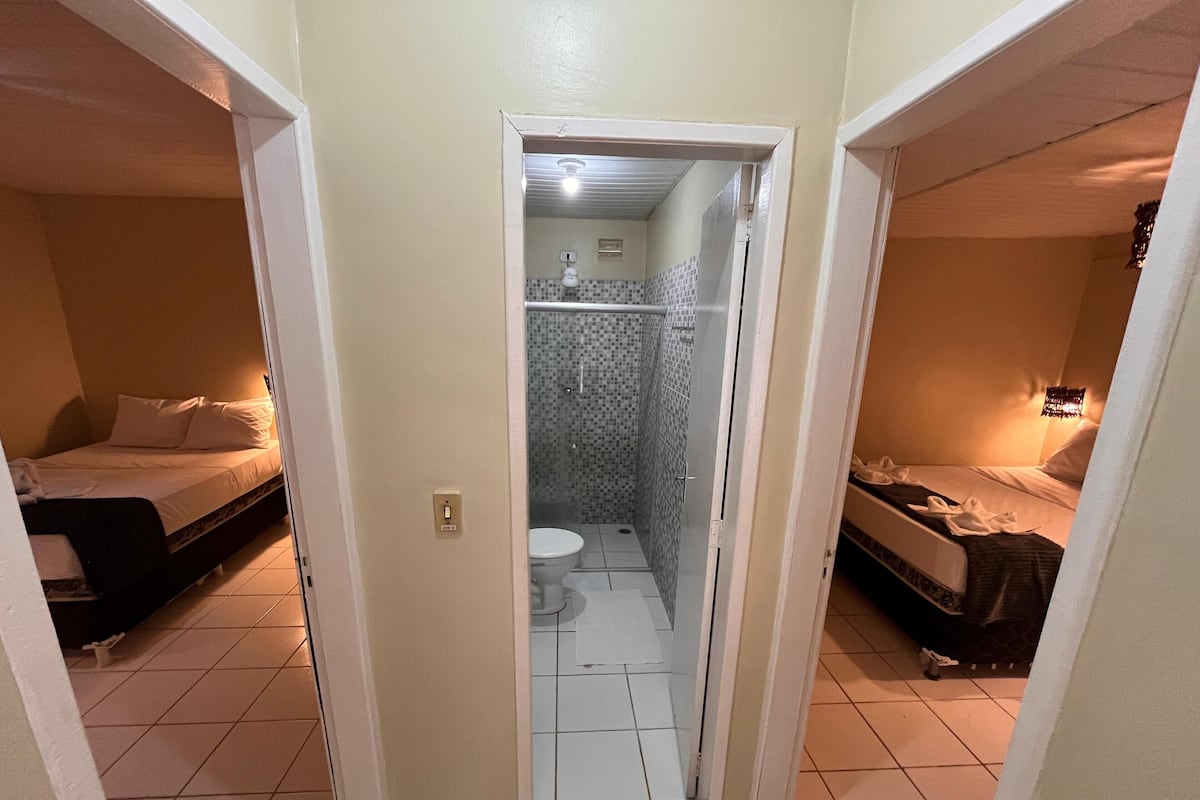 A compact room with two beds, a shower, and a toilet.