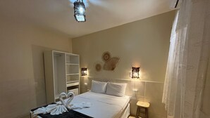 Habitación de hotel con cama, armario, un taburete pequeño y luces de pared decorativas.