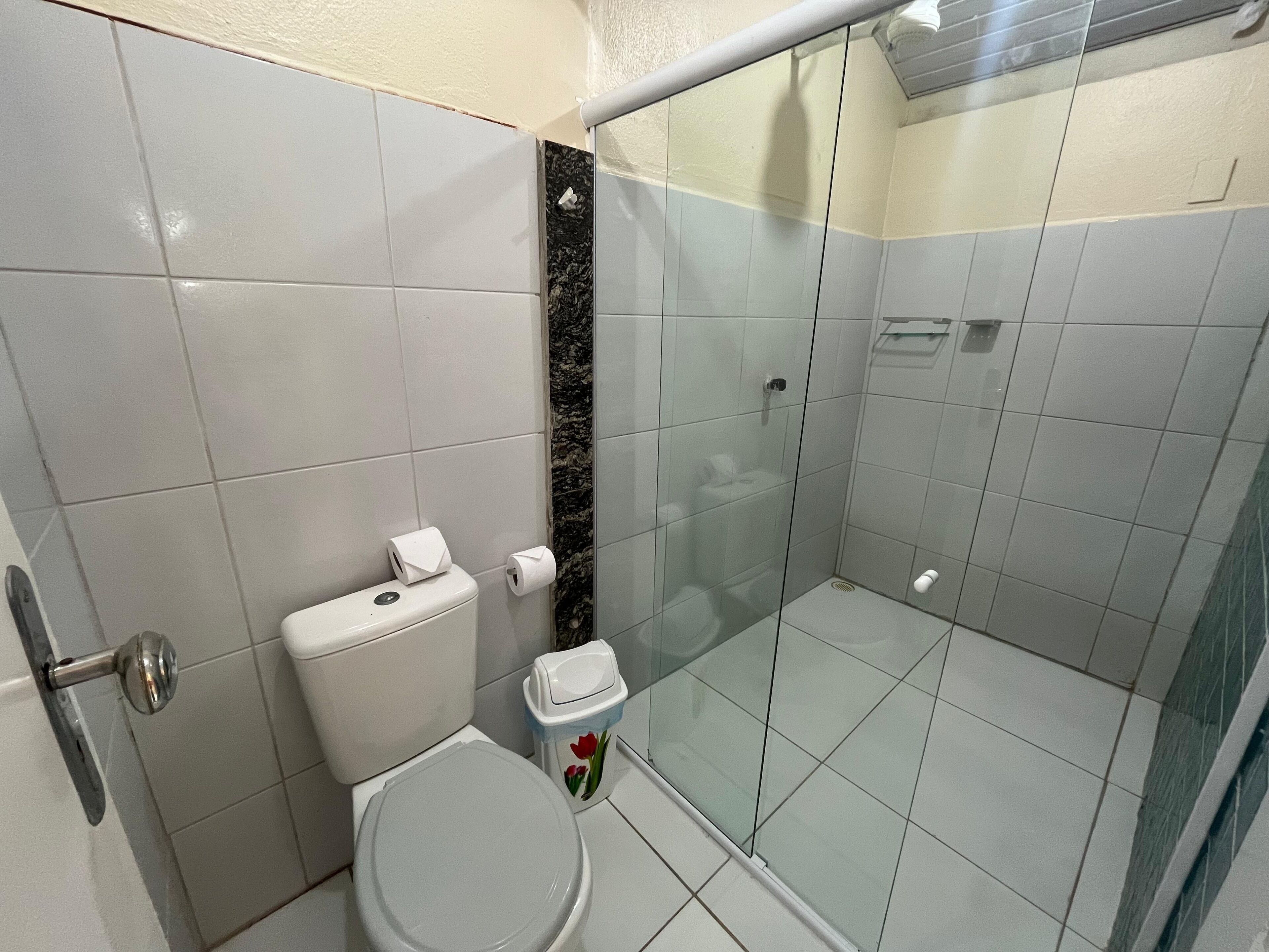 A small, modern bathroom with a toilet, a glass shower enclosure, and a marble accent wall.