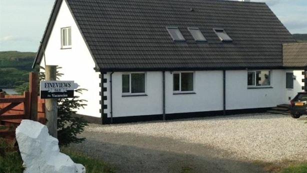 Ein weißes Gebäude mit dunklem Dach, einem Schild mit der Aufschrift 'FINEVIEWS' und 'Freie Zimmer', und einer Schotterauffahrt.