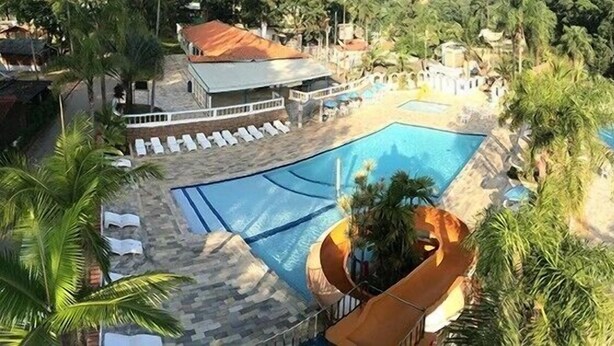 Un área de piscina con varias piscinas, sillas de descanso y un tobogán de agua.