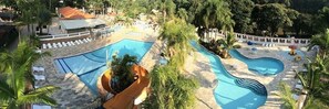 A pool area with multiple swimming pools, lounge chairs, and a water slide. - Quedasdagua Lazer e Hospedagem (Itu)