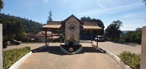 A clock tower with a sign reading "Bem-vindo" at a parking area with a paved walkway and surrounding greenery. - Quedasdagua Lazer e Hospedagem (Itu)