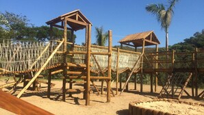 Una estructura de juegos de madera con puentes de cuerda y plataformas.
