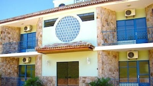 Un edificio de dos pisos con fachada de piedra, ventanas con marcos azules y una ventana circular central.