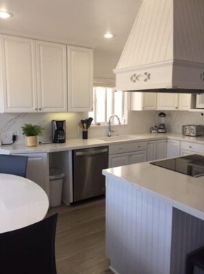 Modern kitchen with white cabinetry, central island, and stainless steel appliances.