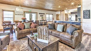 A cozy, rustic interior with wooden ceilings and walls, a dining area with a table and chairs, and a kitchenette with a refrigerator and stove.