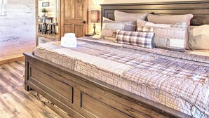 A wooden-paneled bedroom with a large bed, a wooden door, and a framed picture on the wall.