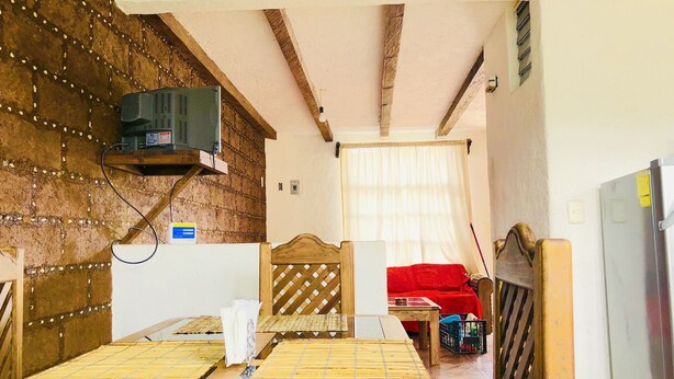 Una stanza con un letto di legno, un divano rosso, un tavolo e un frigorifero.