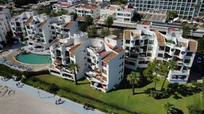 Un hôtel moderne doté de nombreux balcons, d’une piscine et d’un espace de plage.