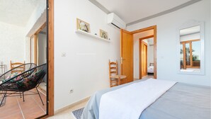 Een slaapkamer met een bed, een stoel, een houten deur en een raam.