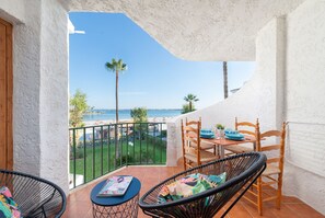 Un balcon avec vue sur la plage, une table avec des chaises et un magazine posé sur la table.