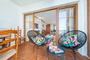 A spacious balcony with wooden furniture, including chairs and a table, and a magazine on the table.