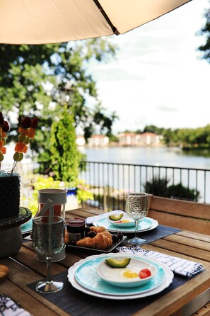 Une table à manger avec des assiettes remplies de nourriture, un verre d’eau et un croissant.