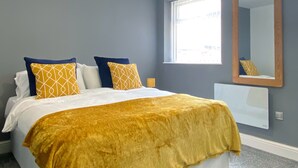 Un dormitorio con cama, ventana y espejo.