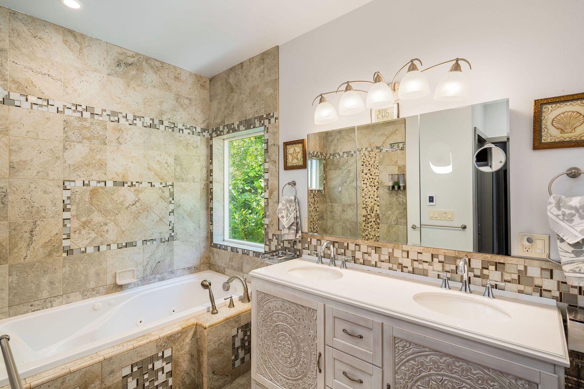 A bathroom with two sinks, a large mirror, and a bathtub.