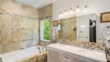 A bathroom with two sinks, a large mirror, and a bathtub.