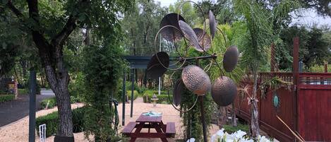 Un jardin agrémenté d’une sculpture en métal, d’une table de pique-nique et d’une clôture en bois.