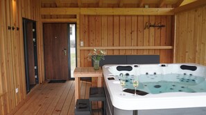 Ein Holzblockhaus-Interieur mit Whirlpool, Holztisch und TĂŒr.