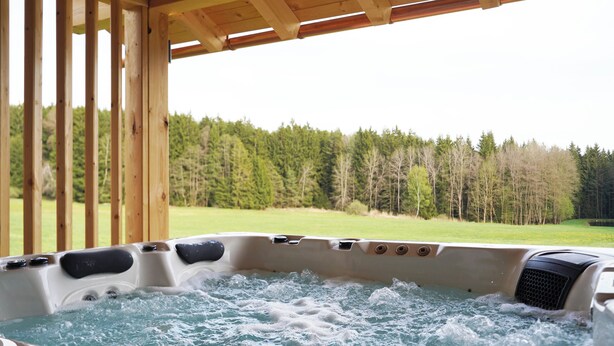 A hot tub with a view of a forested area. - Ferienwohnung Schmalzgrub (Böbrach)