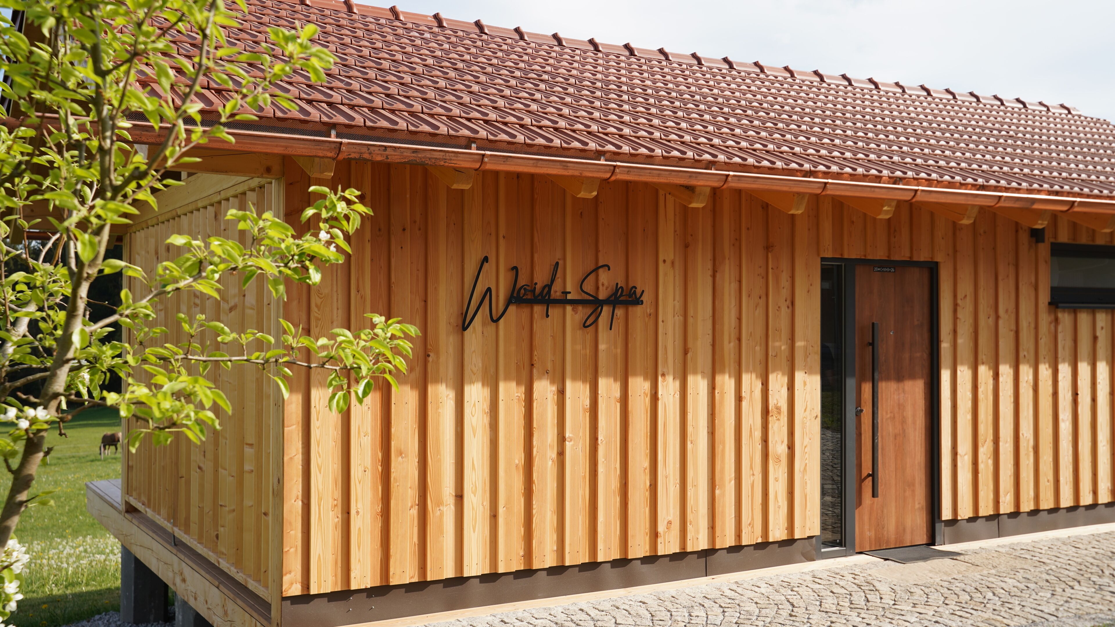 En træbygning med et skilt, der siger 'Woid Spa', og en dør.