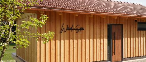 En træbygning med et skilt, der siger 'Woid Spa', og en dør.